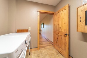 A laundry room with an LG washing machine, a wooden door, and a hallway leading to another room.