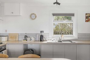 A modern kitchen with a built-in oven, a coffee maker, and a sink. - Beach House & Garden in St Merryn, Private Parking (Rock)