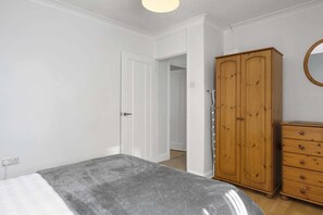 A bedroom with a bed, a wardrobe, and a dresser.