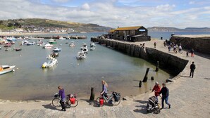 A coastal town with a harbor filled with boats, a stone pier, and a building with a yellow roof. - 18th Century Thatched Cottage, Parking & Garden (Dorset)