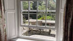 A bay window with multiple panes, a wooden bench, and a table outside. - Grade II Listed House, Tranquil Garden & Parking (Kingsdon)