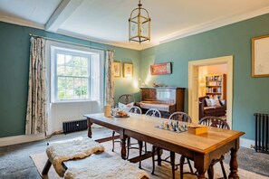 A cozy room with a wooden table, chairs, a radiator, a bookshelf, and a window with curtains. - Grade II Listed House, Tranquil Garden & Parking (Kingsdon)