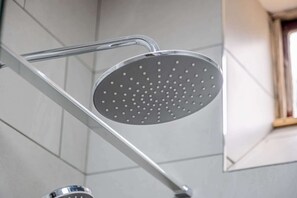 Douchekop met een rond, geperforeerd ontwerp, bevestigd op een chroomfitting.