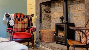 A cozy living room with a fireplace, a red leather armchair, and a wicker basket. - Grade II Listed House, Tranquil Garden & Parking (Kingsdon)