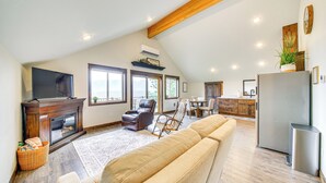 A spacious living area with a fireplace, a large sofa, and a kitchen with a refrigerator. - Balcony & Patio w/ Mtn Views! Bonners Ferry Escape (Bonners Ferry)