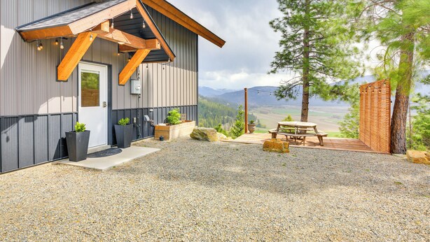 A modern building with a gravel patio, wooden deck, and outdoor seating area. - Balcony & Patio w/ Mtn Views! Bonners Ferry Escape (Bonners Ferry)