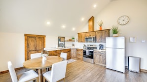 A modern kitchen with wooden cabinets, a dining table with chairs, a microwave, an oven, and a refrigerator. - Balcony & Patio w/ Mtn Views! Bonners Ferry Escape (Bonners Ferry)