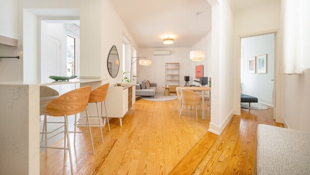 Un salon moderne avec un coin repas, un plancher en bois et un grand miroir.