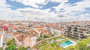 Un quartier résidentiel où se côtoient des bâtiments traditionnels et modernes, avec une piscine et un ciel dégagé.