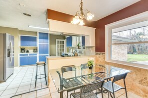 Enjoy meals in the kitchen with a central island, oven, and coffee maker, adjacent to a dining area with a glass-top table and metal chairs.