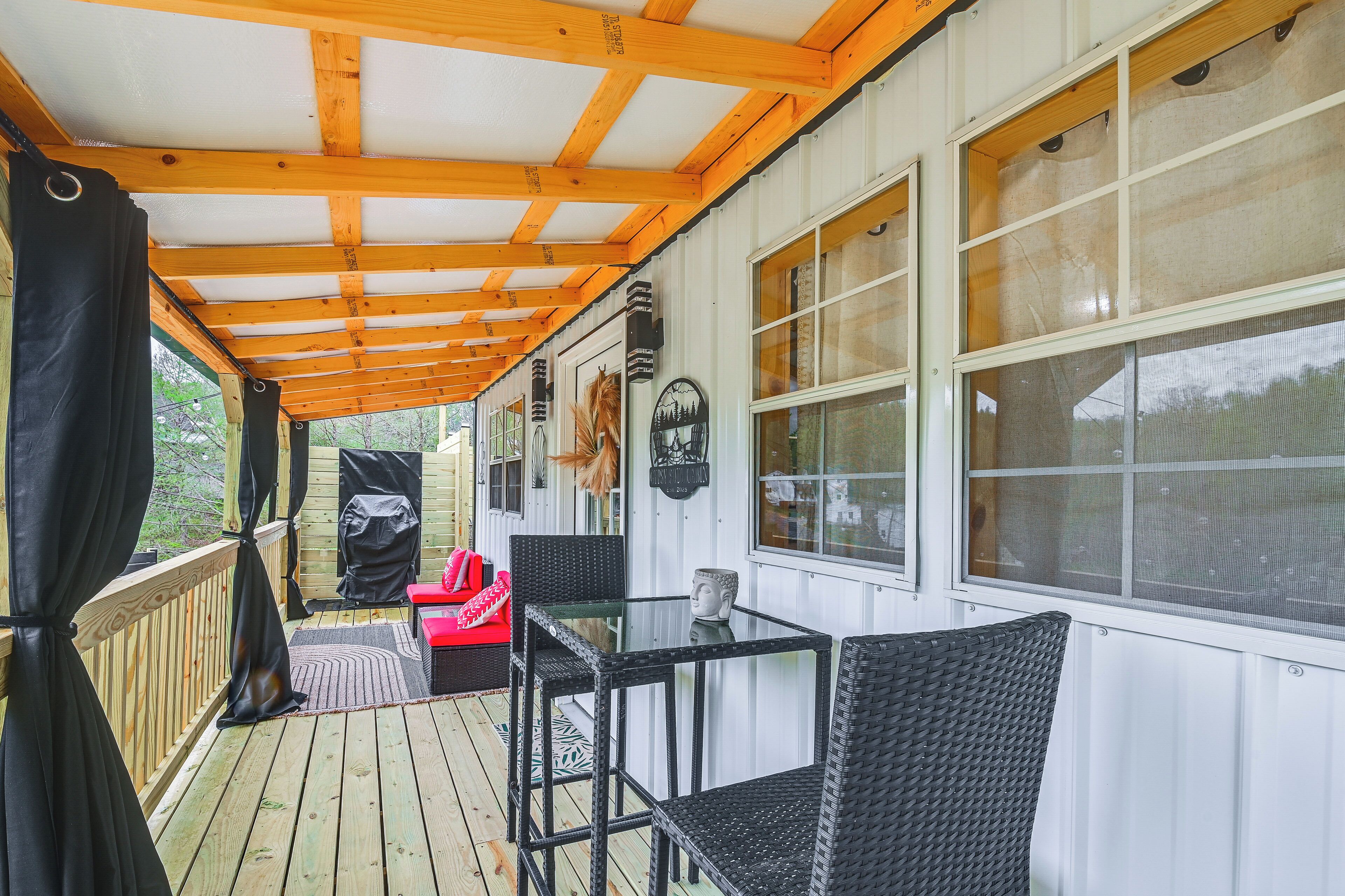A covered porch with a wooden deck, a glass table, and wicker chairs.