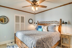 Un dormitorio con cama de madera, ventilador de techo y mesita de noche con lámpara.