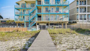 A multi-story hotel with a wooden walkway leading to the entrance. - Balcony w/ Pool & Beach Views: Gulf Shores Condo! (Gulf Shores)