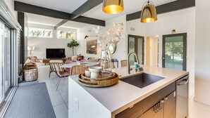 A modern kitchen with a central island, pendant lighting, and a view to the outdoor patio.