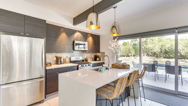 A modern kitchen with a large island, stainless steel appliances, and a view to an outdoor patio area.