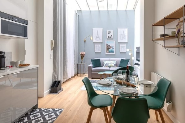 Enjoy meals at the glass table set for four, accompanied by comfortable green chairs.