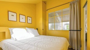 A room with a large bed, yellow walls, and a window with curtains. - Sublime loft - Montmartre (Paris)