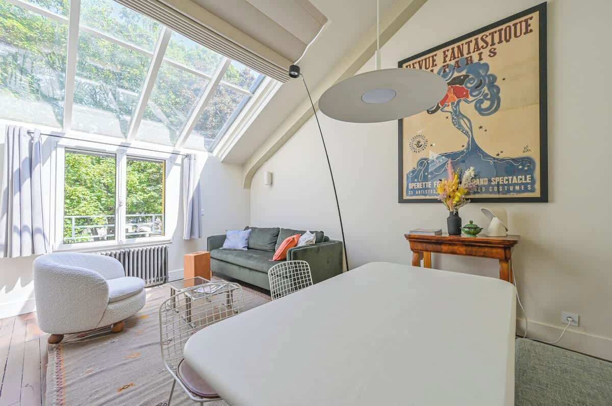 Een moderne loft slaapkamer met dakraam, een groot poster, een bed en een kleine tafel met lamp.