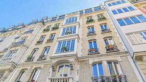 A multi-story building with classic architectural style, featuring balconies with potted plants and large windows. - Sublime loft - Montmartre (Paris)