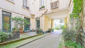 A narrow alleyway with a cobblestone path, flanked by buildings with green doors and potted plants. - Sublime loft - Montmartre (Paris)