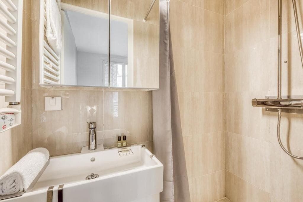 A modern bathroom with a bathtub, a shower, and a large mirror.
