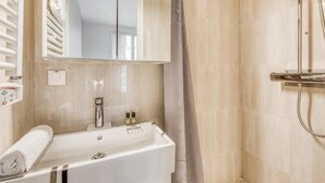 Un baño moderno con bañera, ducha y un espejo grande.