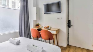 Ein Hotelzimmer mit einem Bett, einem Schreibtisch mit zwei Stühlen, einem Fernseher und einer Tür.
