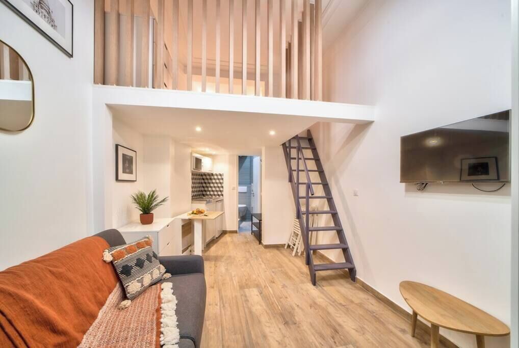 En modern lägenhet med ett vardagsrum i loftstil, ett kök och en trappa.