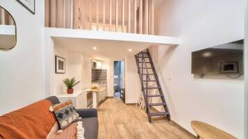 En modern lägenhet med ett vardagsrum i loftstil, ett kök och en trappa.