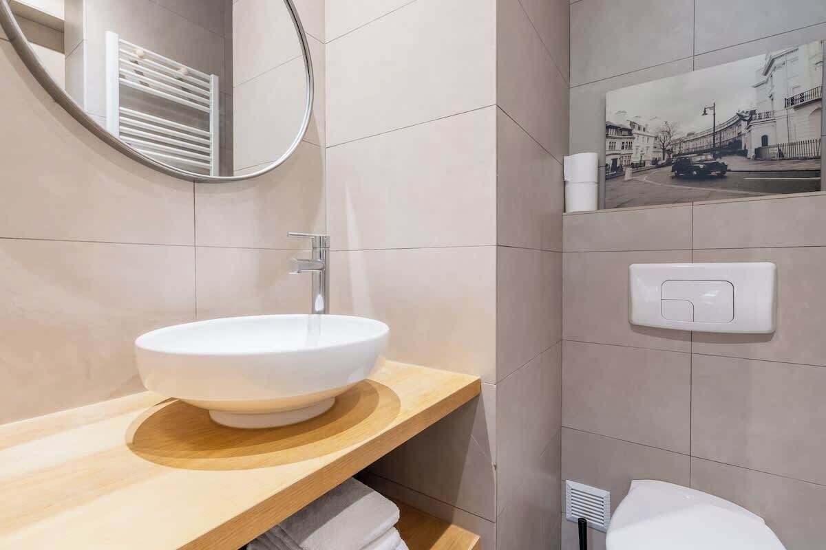 Une salle de bain moderne avec un lavabo rond, un miroir et un radiateur fixé au mur.