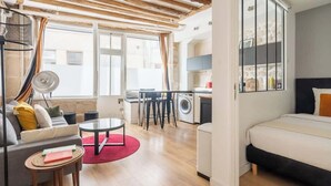 A modern apartment with a living room, kitchen, and bedroom. The living room has a sofa, a coffee table, and a dining area. The kitchen has a washing machine and a dining table. The bedroom has a bed and a window. - ParisConciergerie - 1BR apartment with AC (Paris)