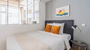 A bedroom with a bed, pillows, a desk, a lamp, and a window. - ParisConciergerie - 1BR apartment with AC (Paris)