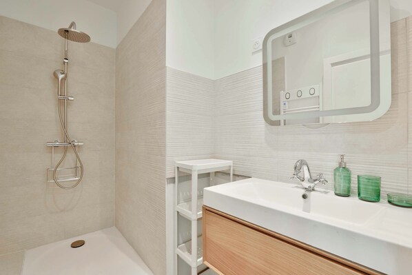 A bathroom with a shower, a sink, and a mirror.