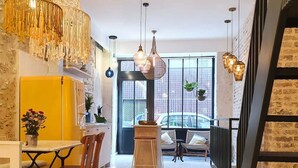 Una cocina moderna con un refrigerador amarillo, sillas de madera y lámparas colgantes.