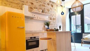 Una cocina moderna con un refrigerador amarillo, taburetes de madera y un ventanal amplio.