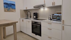 Eine moderne Küche mit weißen Schränken, einem schwarzen Wasserhahn, einer Kaffeemaschine und einem Backofen.
