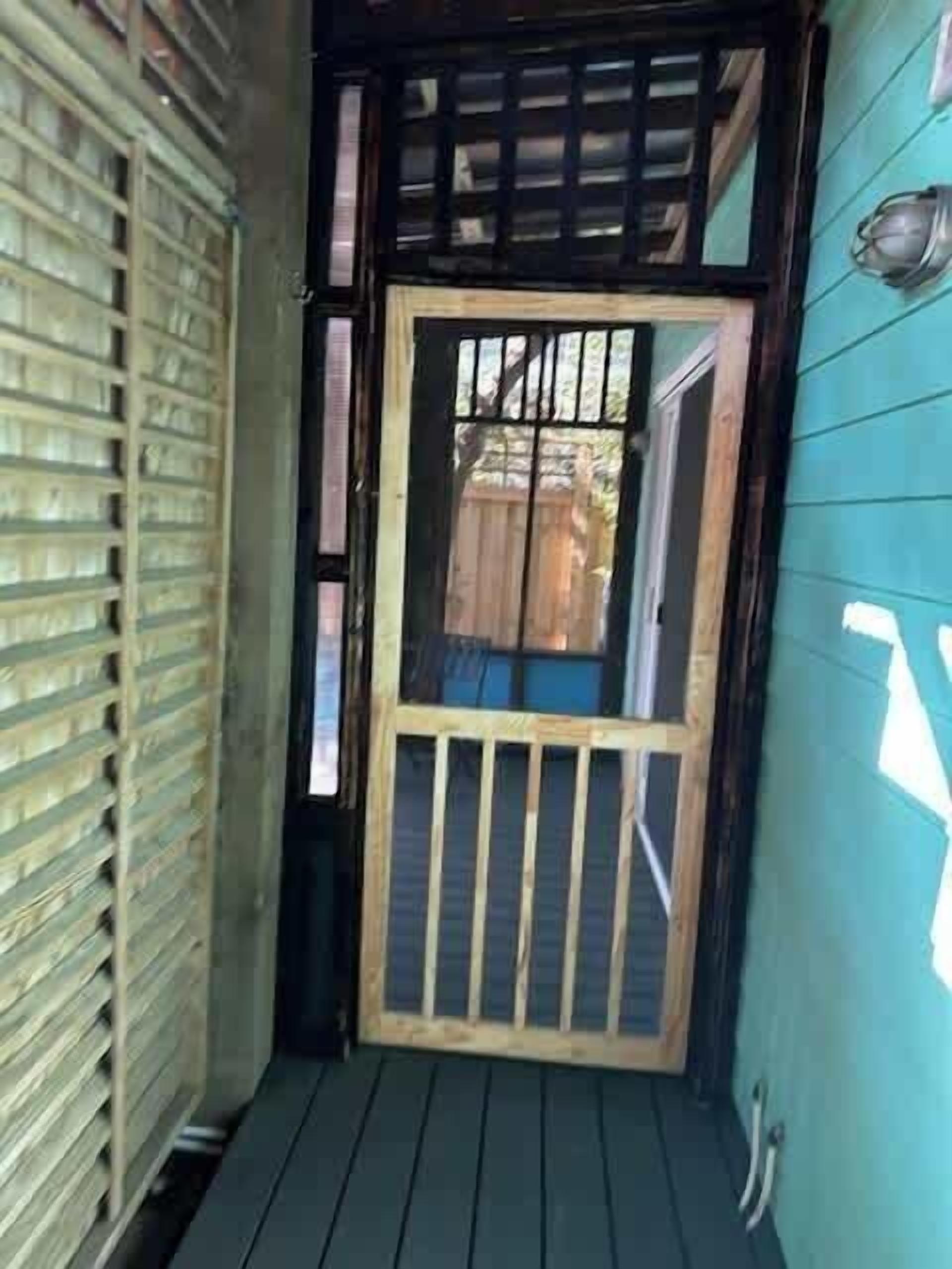 A wooden door with a metal gate, a wooden staircase, and a metal railing.