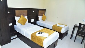 Two single beds with headboards, white bedding, and gold throw pillows. - Hotel Embassy Suites (Mumbai)