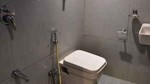 A small, modern bathroom with a toilet, a sink, and a shower. - Hotel Embassy Suites (Mumbai)