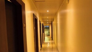 A long, narrow hallway with doors on both sides, leading to a bright room at the end. - Hotel Embassy Suites (Mumbai)