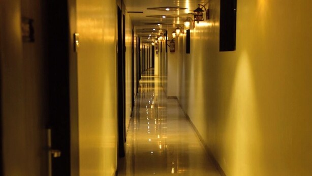 A long, well-lit corridor with doors on the left and wall-mounted lights on the right. - Hotel Embassy Suites (Mumbai)