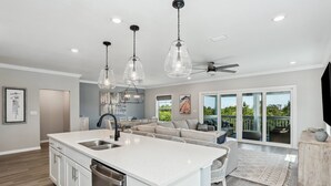 Cocina moderna con una isla central, electrodomésticos de acero inoxidable e iluminación colgante.