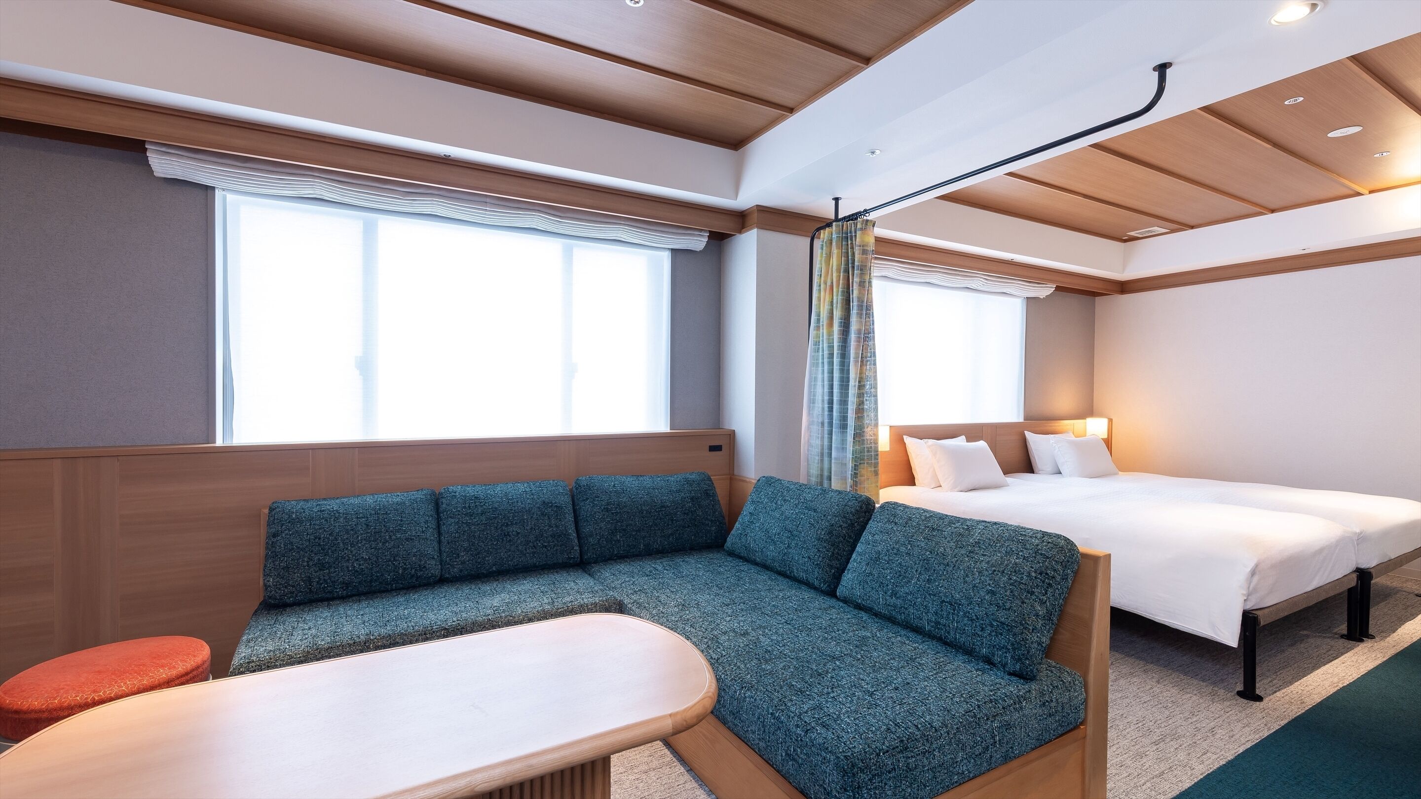 A modern hotel room with a sofa, a bed, and a small table.