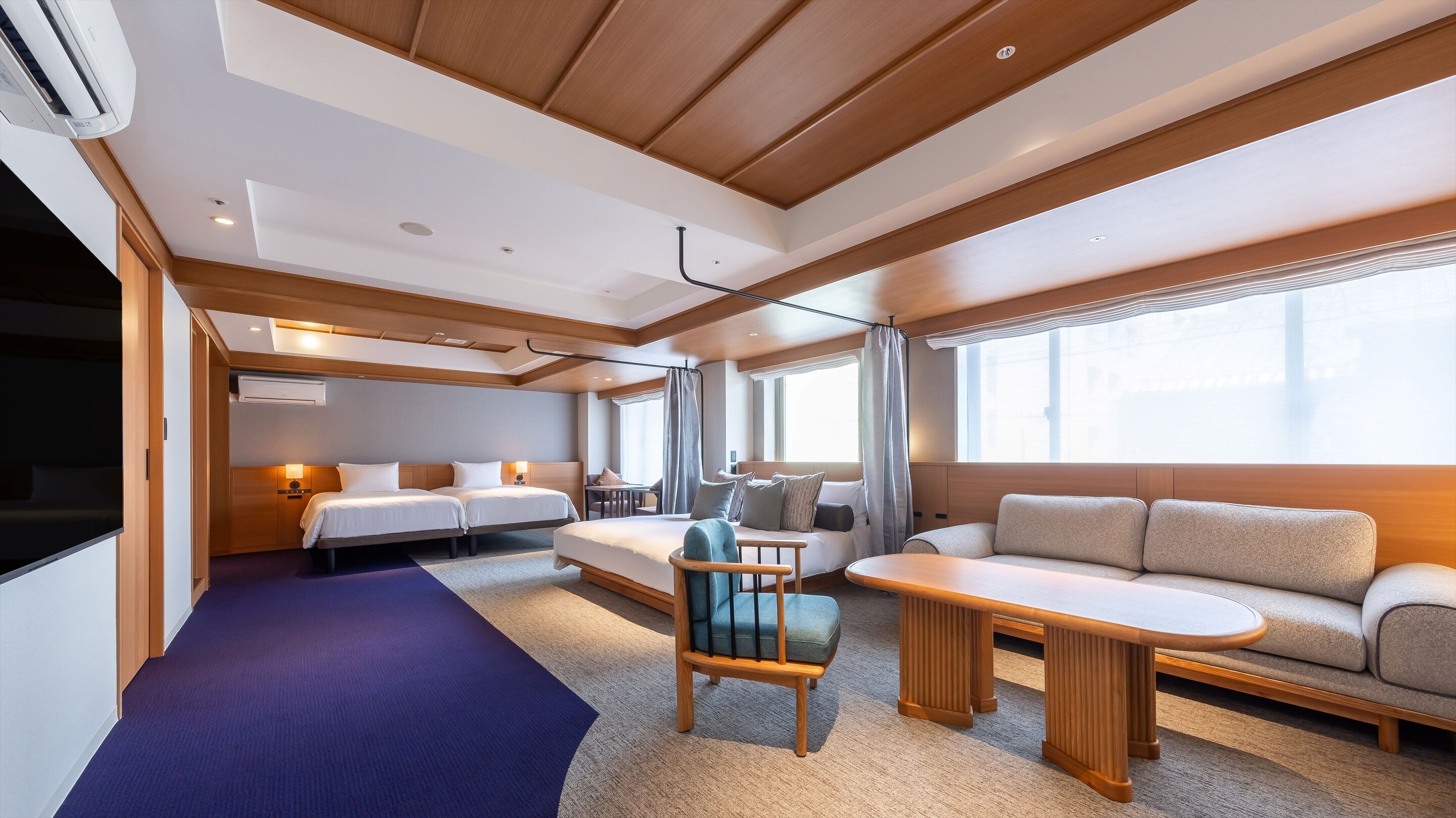 A modern hotel room with a bed, sofa, and a small table.