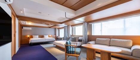 A modern hotel room with a bed, sofa, and a small table.