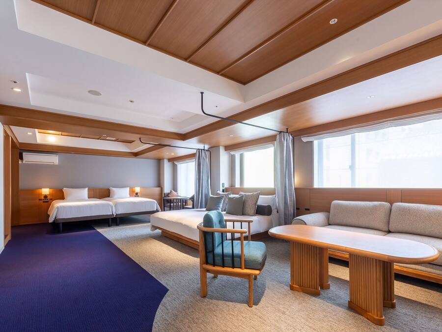 A modern hotel room with a bed, sofa, and a small table.