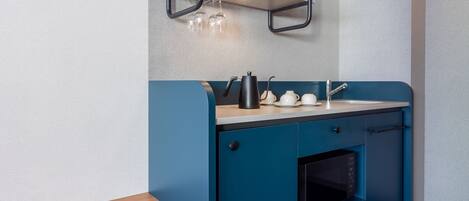 A compact kitchenette with a microwave, a kettle, and a coffee maker on the counter.