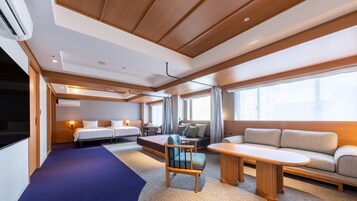 Una habitación de hotel moderna con cama, sofá y zona de comedor.