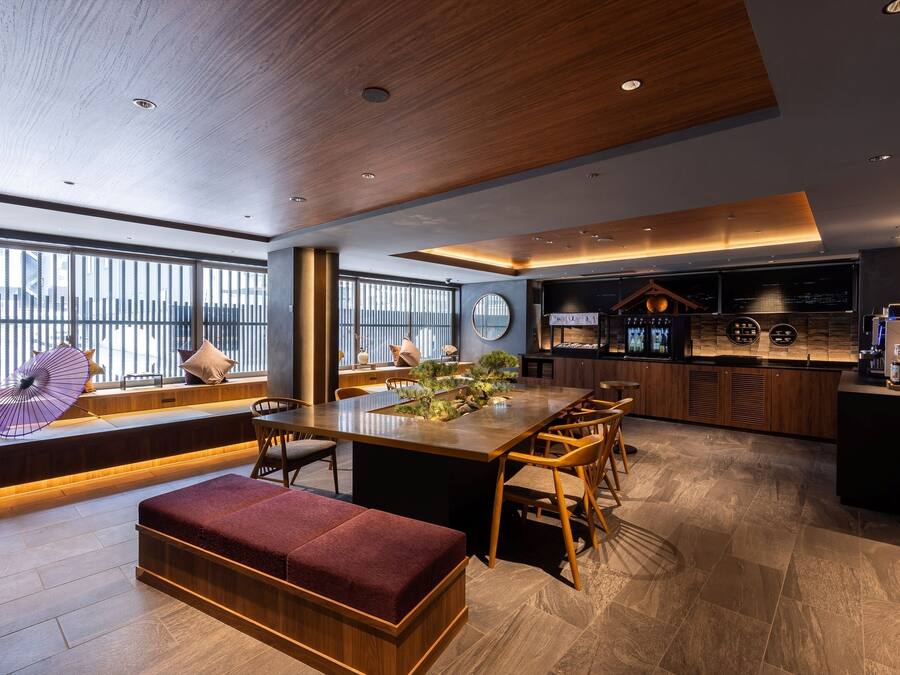 A modern kitchen with a central island, seating area with a bench, and large windows providing natural light.