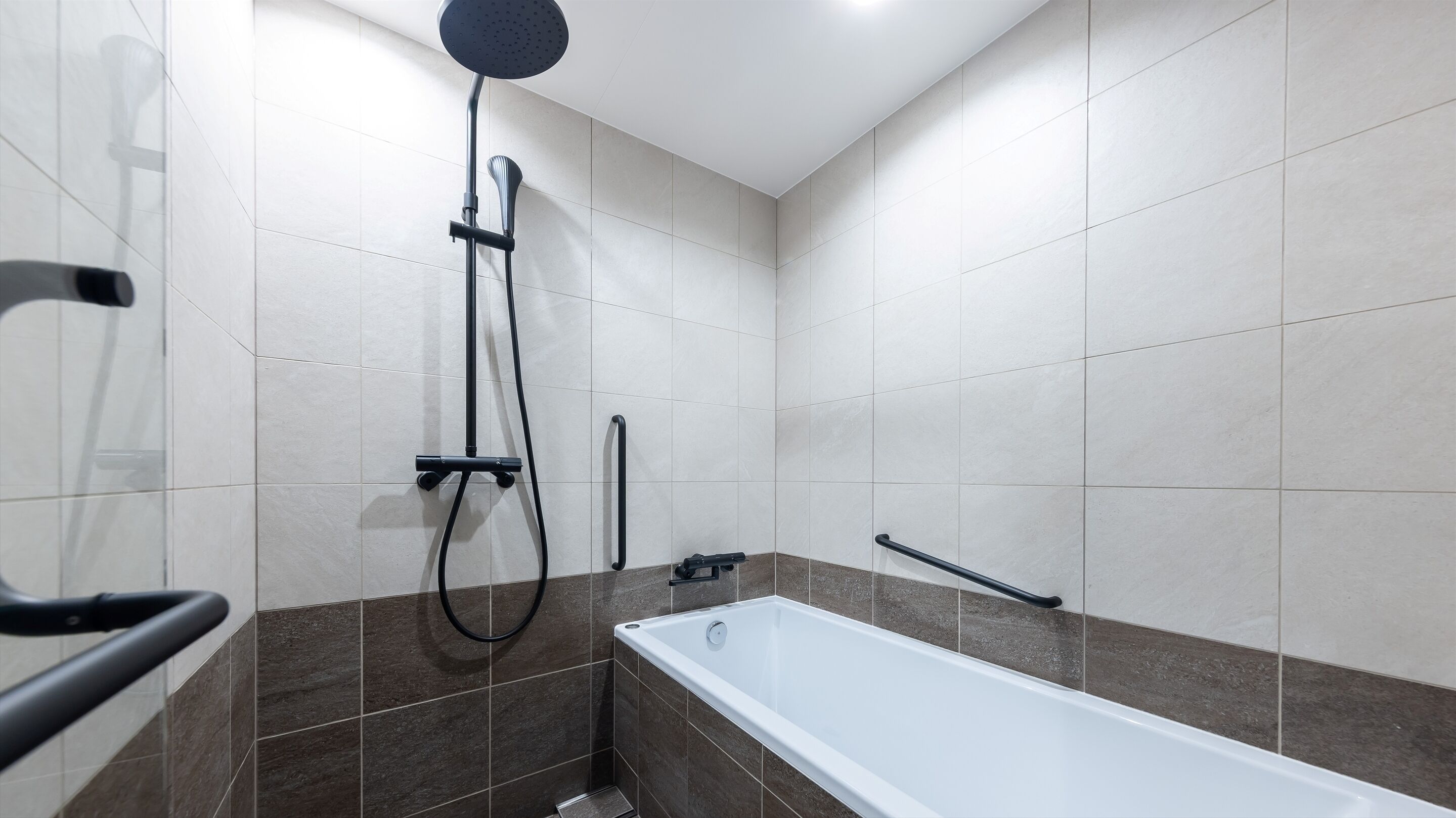 Une salle de bain moderne équipée d’une baignoire, d’une douche et de barres d’appui.